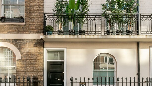 En toetages bygning med facade af mursten og en balkon med blomsterkrukker.