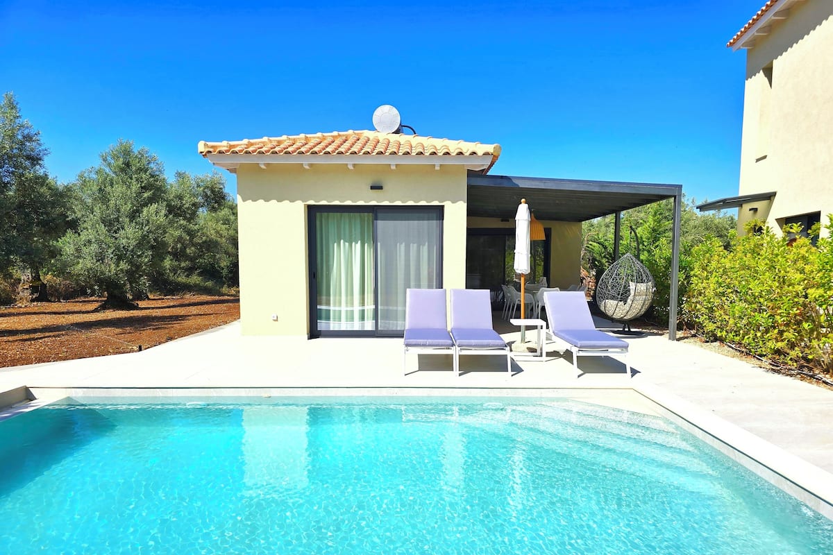 A swimming pool with lounge chairs and a covered seating area.