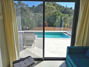 A room with a sliding glass door leading to a pool area. - Anmaria Luxury (Lefkada)