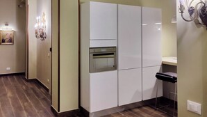 Una cucina moderna con mobili bianchi, forno integrato e uno sgabello da bar.