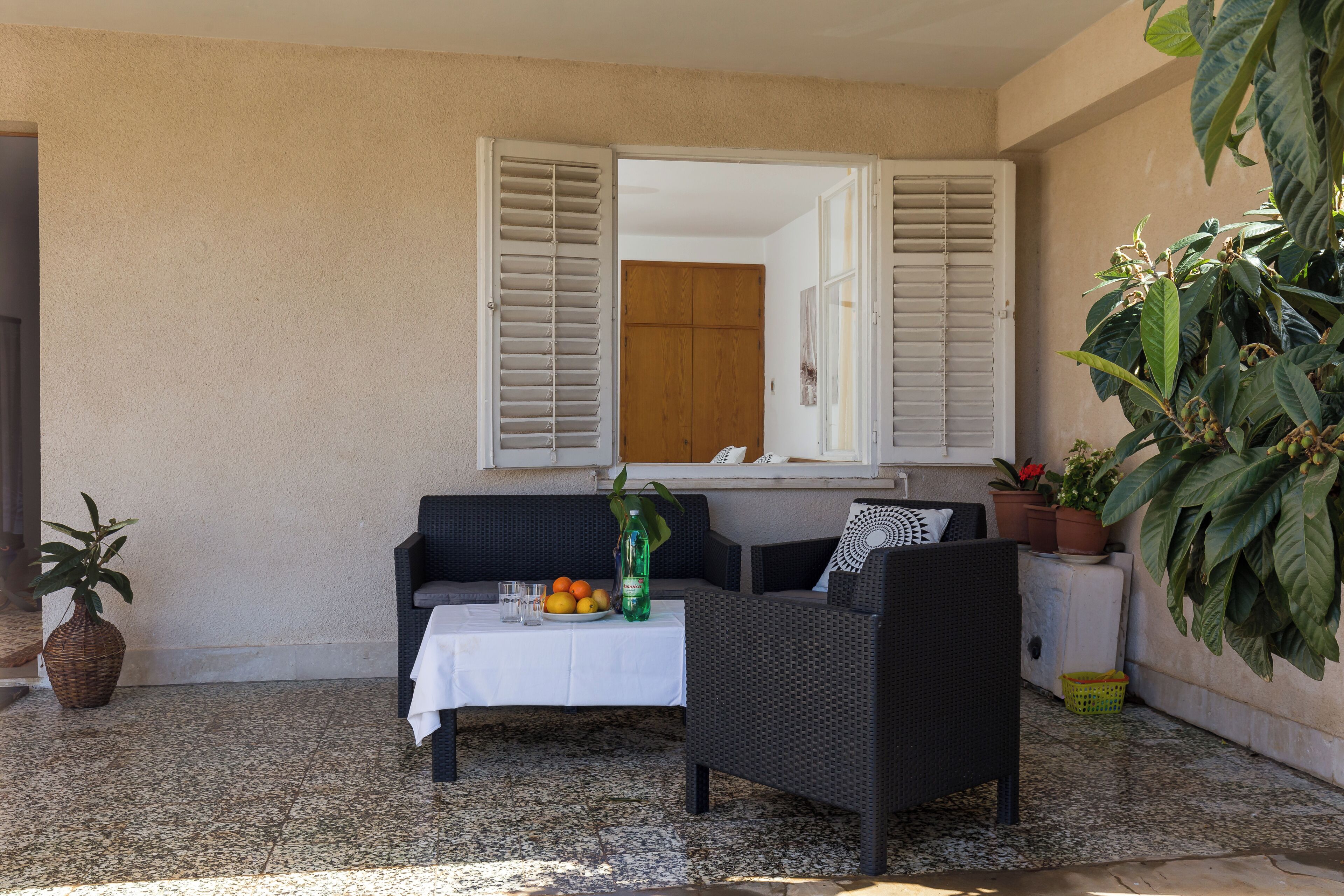 Un espace extérieur abrité, aménagé avec une table, des chaises et un pot de fleurs.