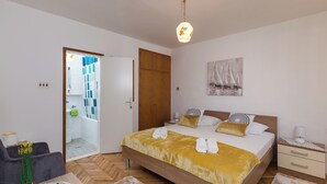 A bedroom with a wooden bed, a nightstand, a bedside table, and a hanging light fixture.