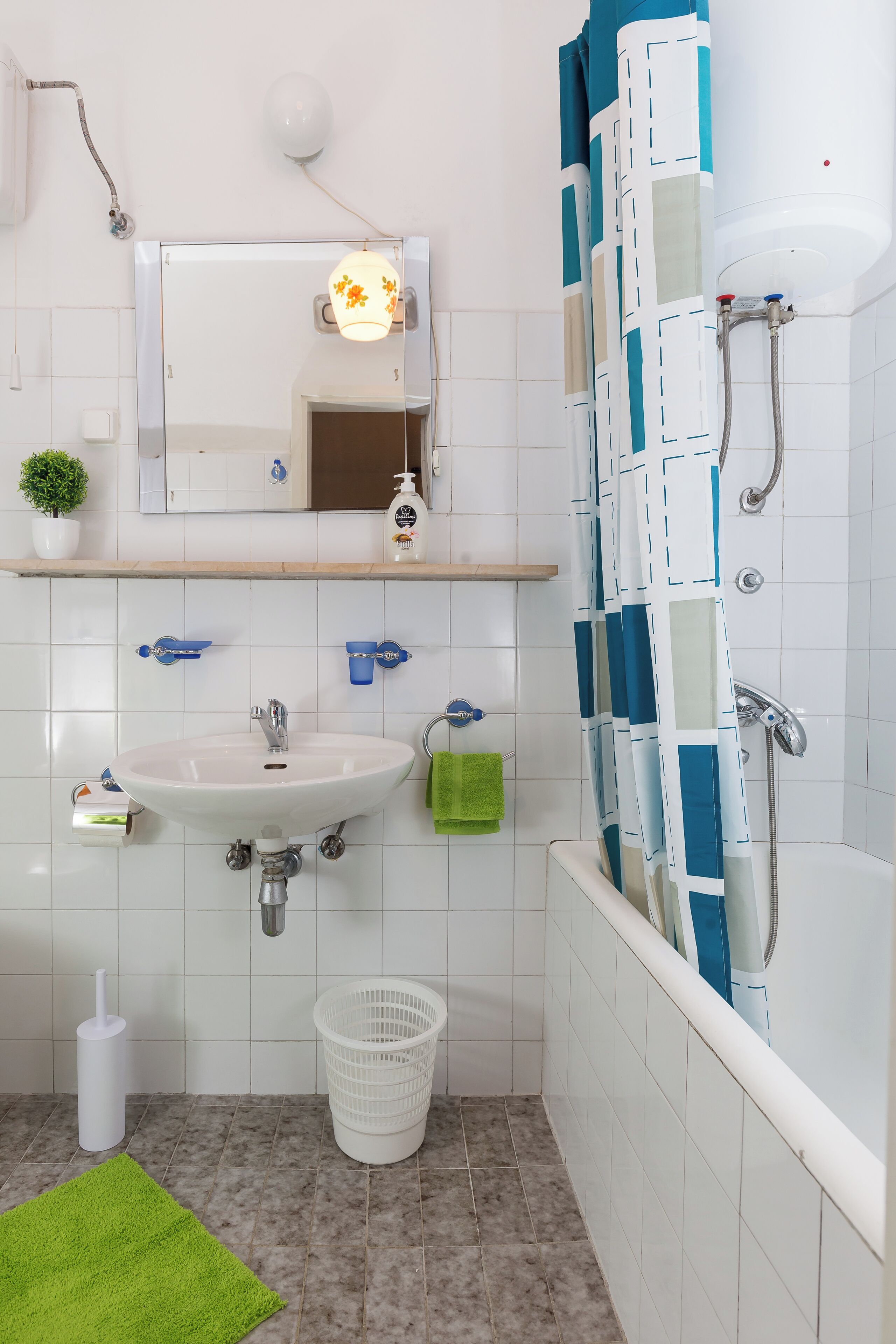 Un baño con lavamanos blanco, espejo y zona de ducha.