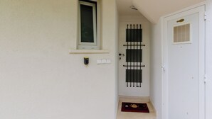 A white door with a window above it, a small window with blinds, and a doorbell. - Apartment Bim (Dubrovnik)