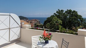 A terrace with a table and chairs, overlooking a coastal town and the sea. - Apartment Bim (Dubrovnik)