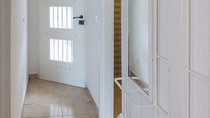 A hallway with a white door, a white wall with a mirror, and a tiled floor. - Apartment Bim (Dubrovnik)