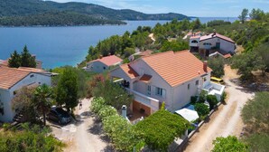 Un village côtier avec des maisons, une route et une vue sur la mer et les collines.