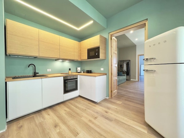 A modern kitchen with wooden cabinets, a built-in oven, and a white refrigerator.