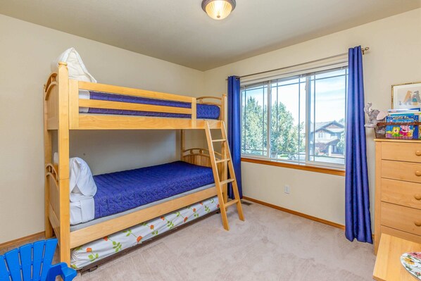 Une chambre avec un lit superposé, une fenêtre, une commode et une échelle.