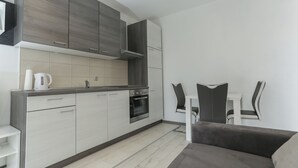 Una cocina moderna con gabinetes grises, un horno empotrado y una encimera blanca.
