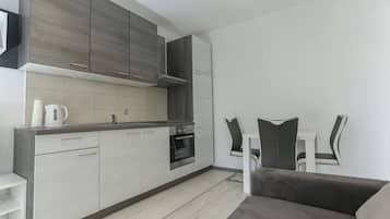 Una cocina moderna con gabinetes grises, un horno empotrado y una encimera blanca.