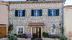 A stone building with three windows, a wooden door, and a small balcony. - Art Apartment Seasoul (Dubrovnik)