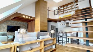 Un apartamento loft moderno con cama en altillo, zona de comedor y cocina.