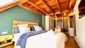 Un dormitorio con techo de madera, una cama con manta azul, una mesita de noche y un armario con papel tapiz estampado.
