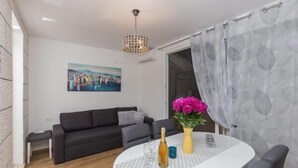 Ein modernes Wohnzimmer mit einem grauen Sofa, einem weißen Tisch mit Blumenvase und einem Gemälde an der Wand.