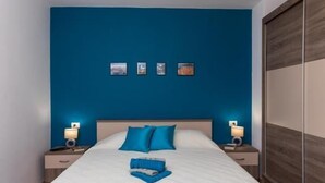 Ein Schlafzimmer mit einem großen Bett, zwei Nachttischen mit Lampen, einem Kleiderschrank und vier gerahmten Bildern an der Wand.