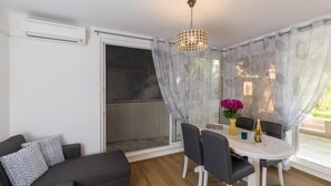 Ein Essbereich mit einem runden Tisch, Stühlen, einer Chandelüster und einer Couch.