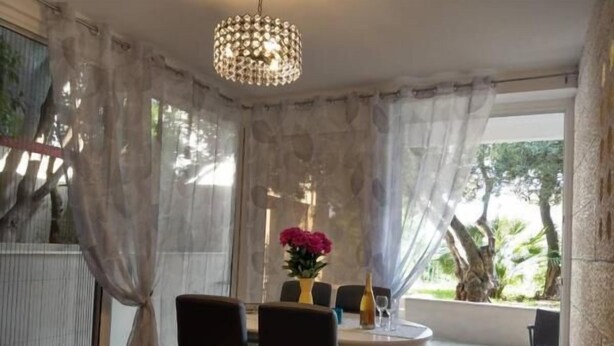 Ein Essbereich mit einem runden Tisch, vier Stühlen, einer Chandelüster und einer Blumenvase.