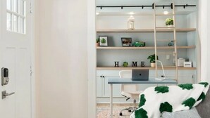 Una oficina en casa moderna con un escritorio, estanterías y una escalera.