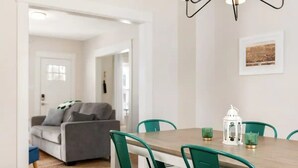 Un comedor con una mesa de madera, sillas verdes y un farol blanco.