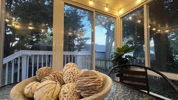 Un’area esterna coperta con un tavolo in vetro su cui è posata una ciotola con oggetti decorativi.
