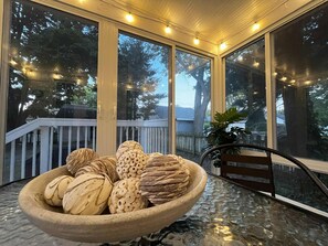 A covered outdoor area with a glass table holding a bowl of decorative items. - Walk to Notre Dame! Harter Heights Hideaway (South Bend)