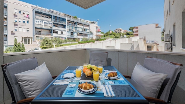 Ein Balkon mit einem Frühstückstisch, ausgestattet mit Croissants, Obst und Saft.