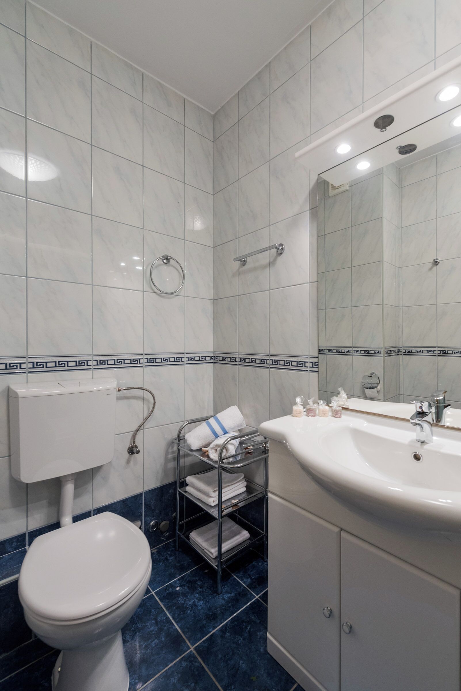 A bathroom with a toilet, sink, and mirror.