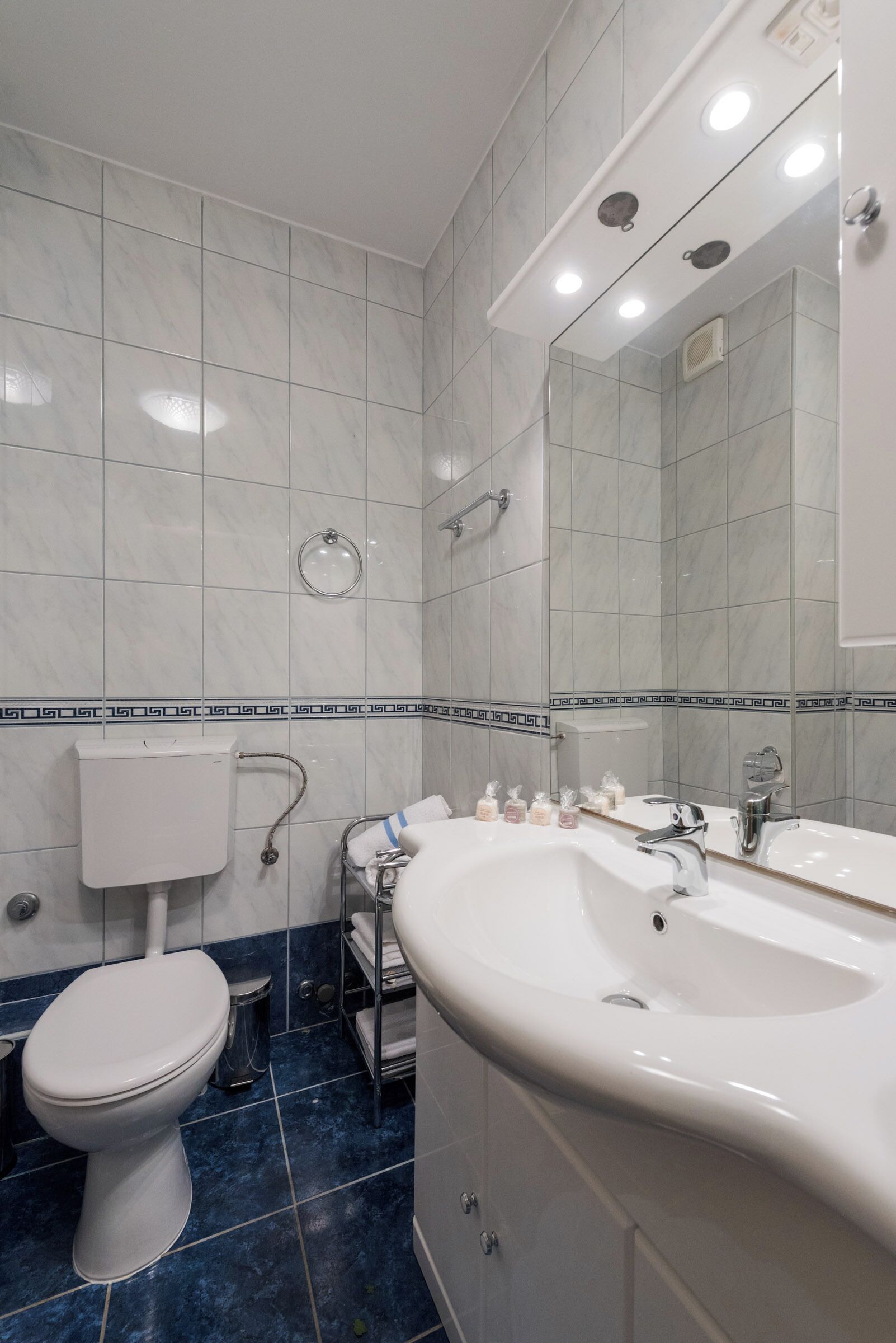 A modern bathroom with a white toilet, a large sink with a mirror, and a shower.