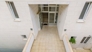 A building entrance with a tiled floor, a staircase leading to an upper level, and a door with glass panels. - Grand Apartment (Dubrovnik)
