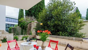 An outdoor patio with red chairs, a white table, and a vase of flowers. - Grand Apartment (Dubrovnik)