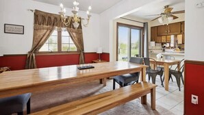 Un comedor con una mesa de madera, sillas y una araña.