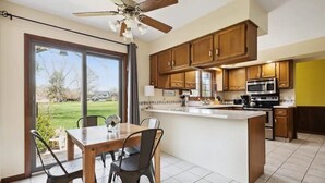Una cocina con armarios de madera, una isla central y un comedor con sillas.