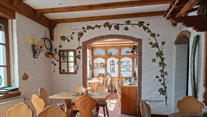Un comedor rústico con muebles de madera, un arco de ladrillo y vistas a la cocina.