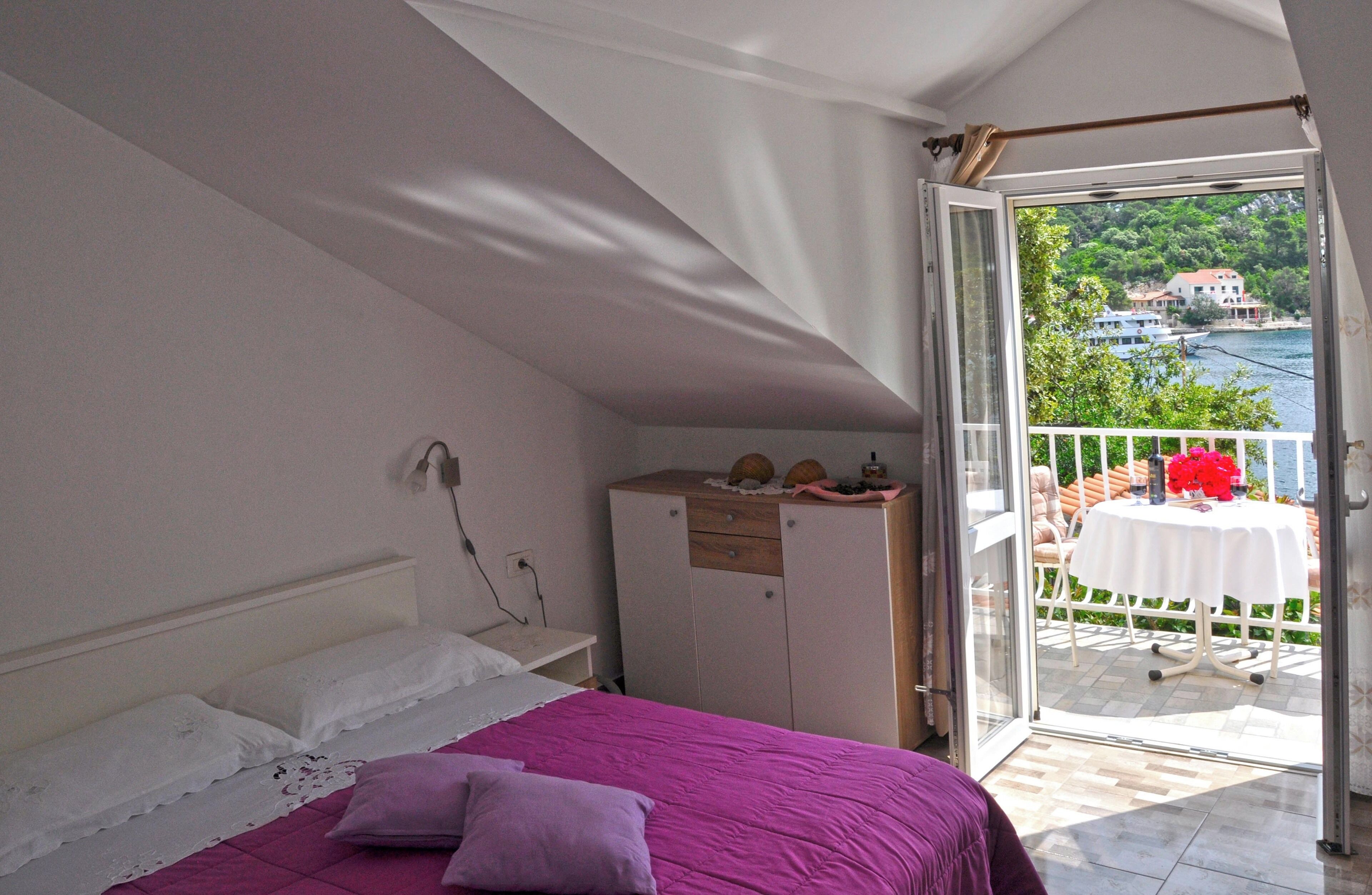 Un dormitorio con cama, armario y balcón con mesa y sillas.