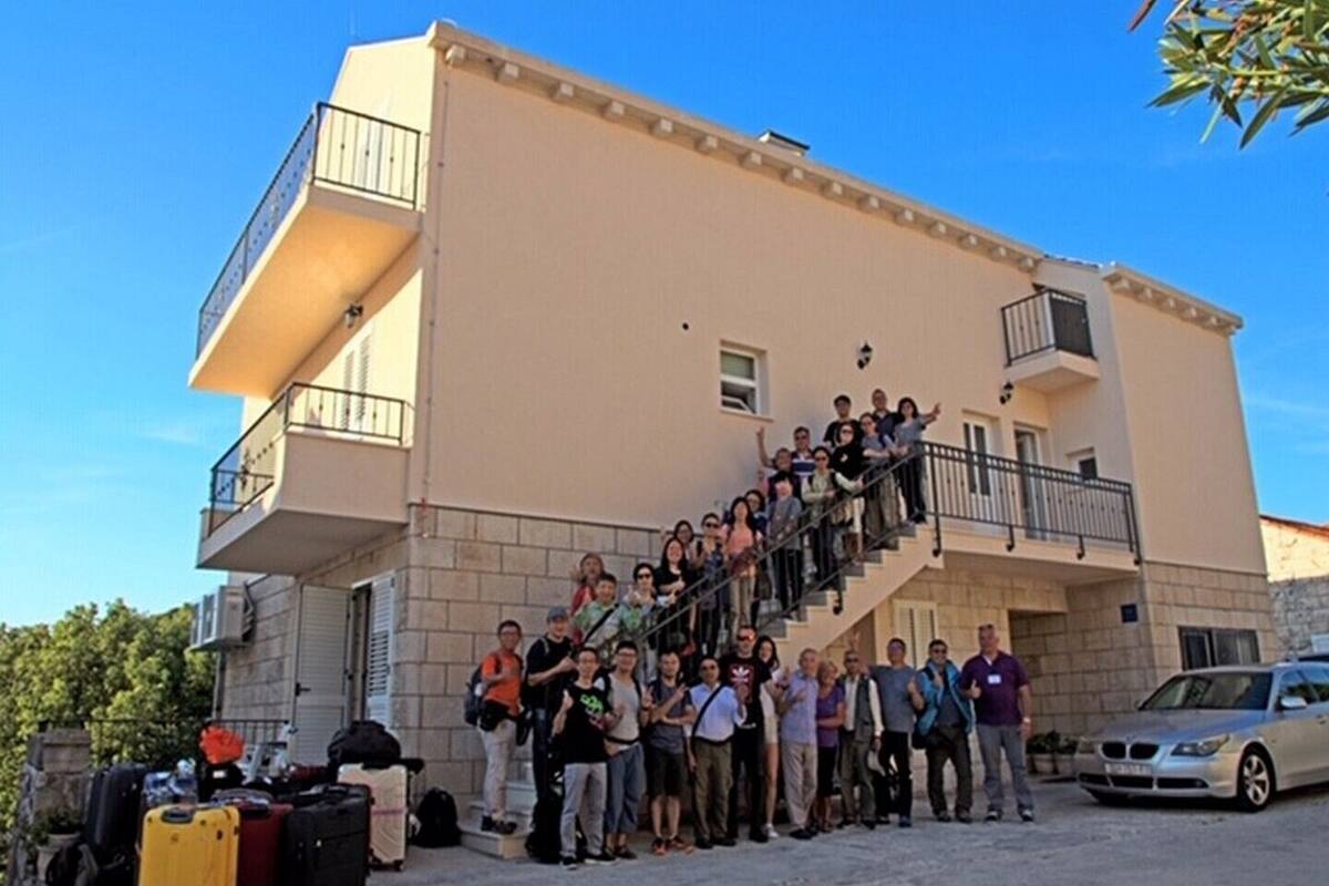 A group of people standing on a staircase outside a building with a beige facade and balconies.