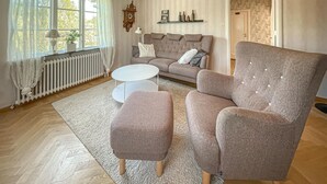 Un salon comprenant un canapé, un fauteuil, un pouf et une table basse.