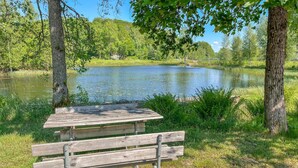 Une table de pique-nique en bois, avec des bancs, dans un parc au bord d’un lac.