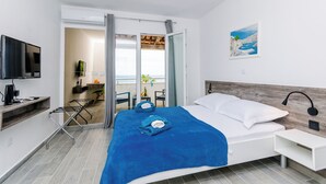 Habitació d'hotel moderna amb llit, televisió, escriptori i vistes al balcó.