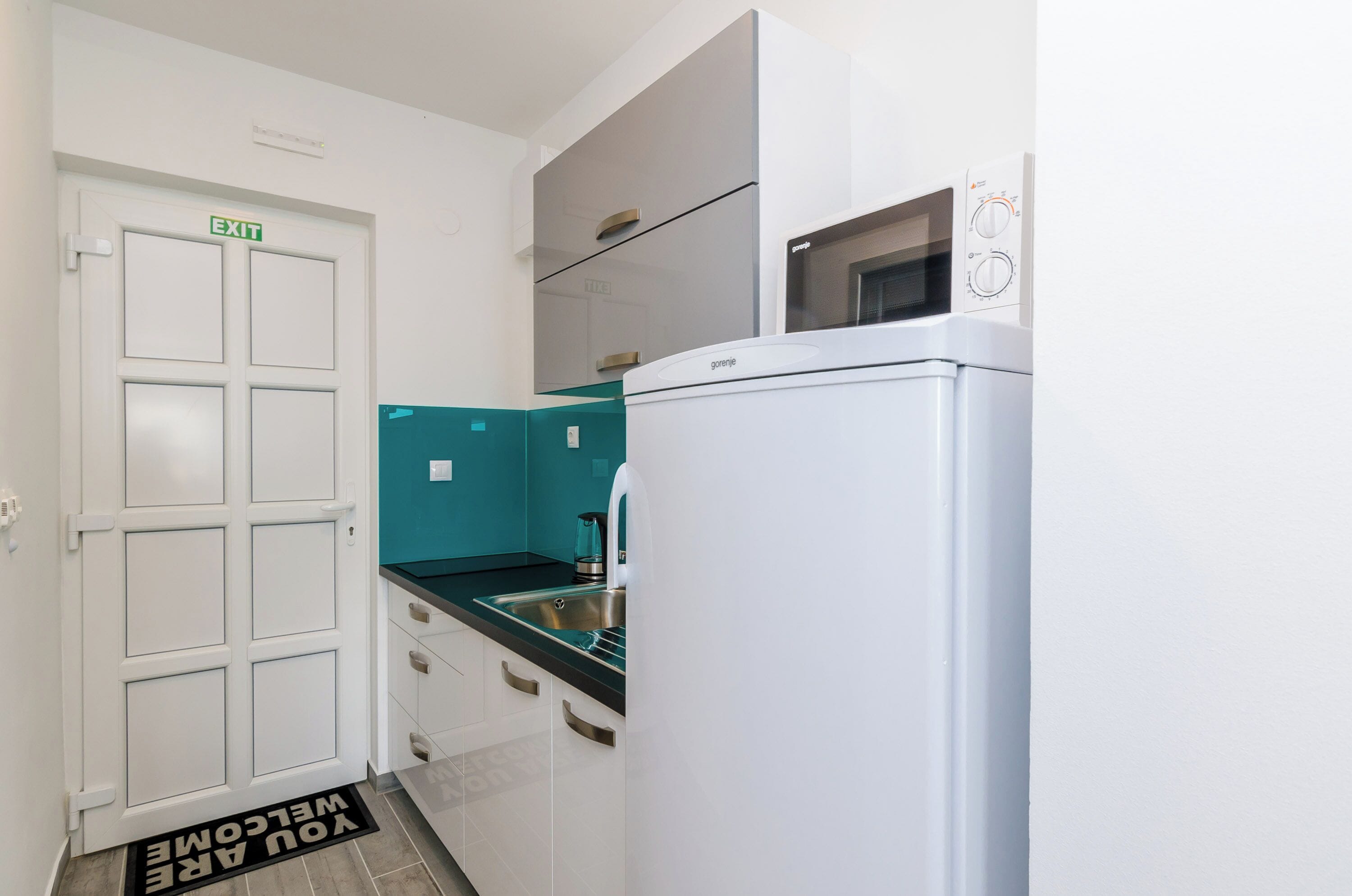 A compact kitchen with a white refrigerator, a built-in oven, and a sink.