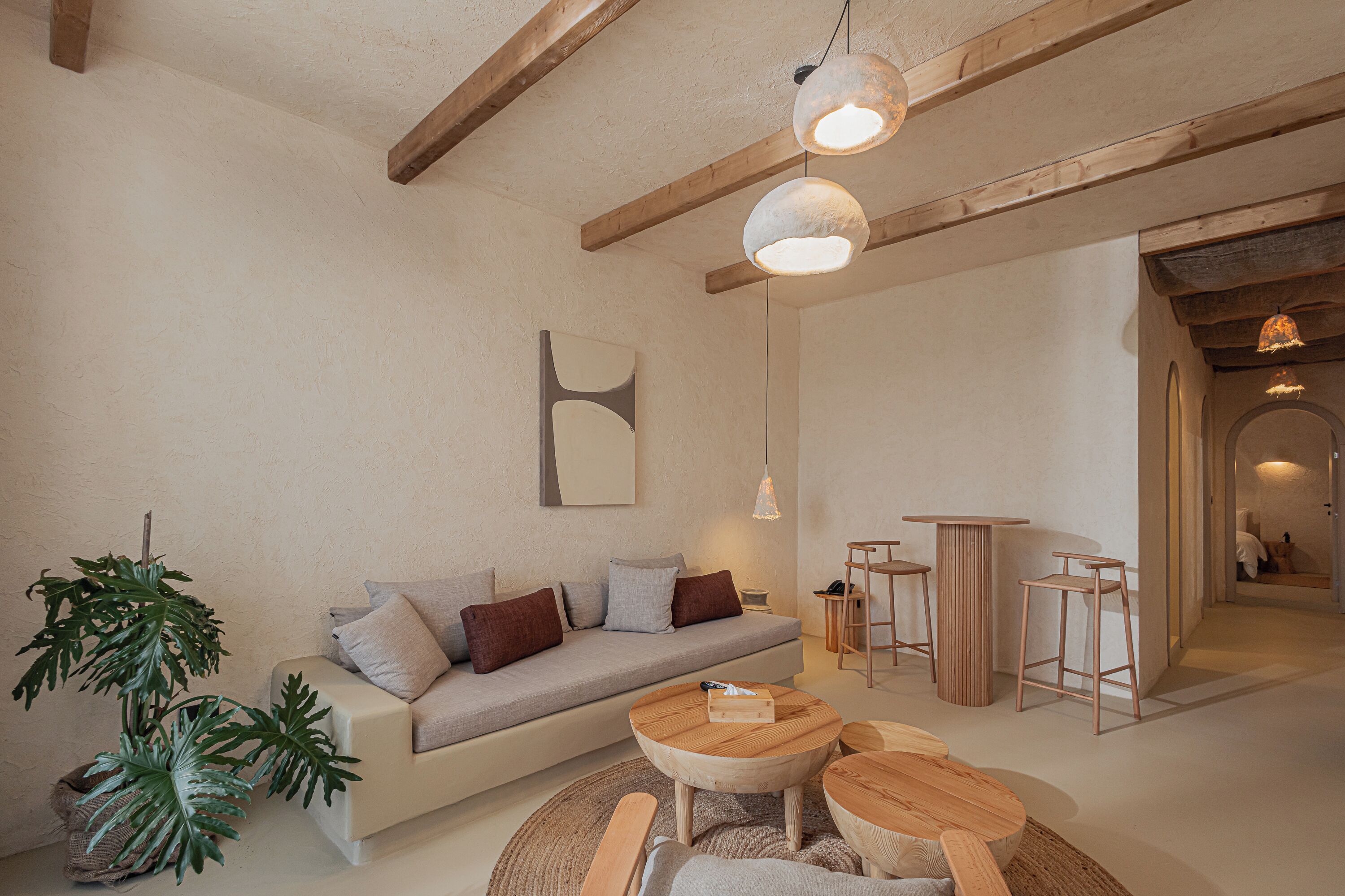 Un espace de vie moderne comprenant un canapé, une table basse et des tabourets de bar.