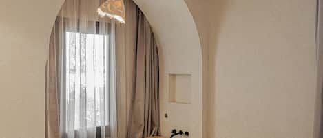 Un dormitorio con una bañera de madera, una cama y un ventanal con cortinas.