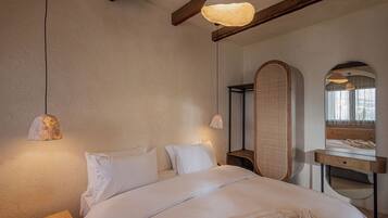 Un dormitorio con una cama grande, cabecera de madera, mesitas de noche, un espejo y una lámpara colgante.