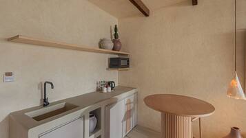 A modern kitchen with a built-in sink, wooden shelves, a microwave, and a round wooden table.
