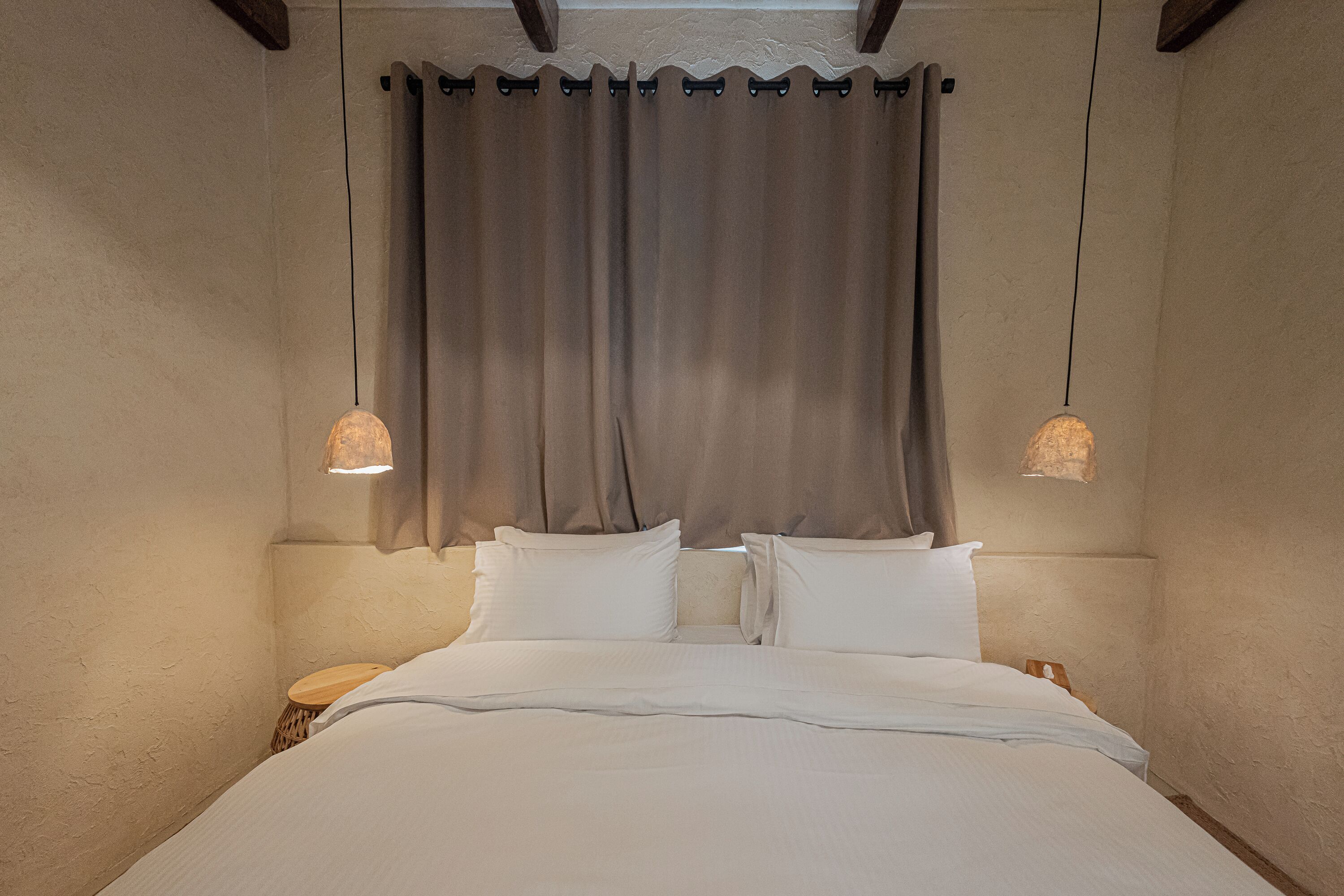 Un dormitorio con cama, cortinas y dos lámparas colgantes.