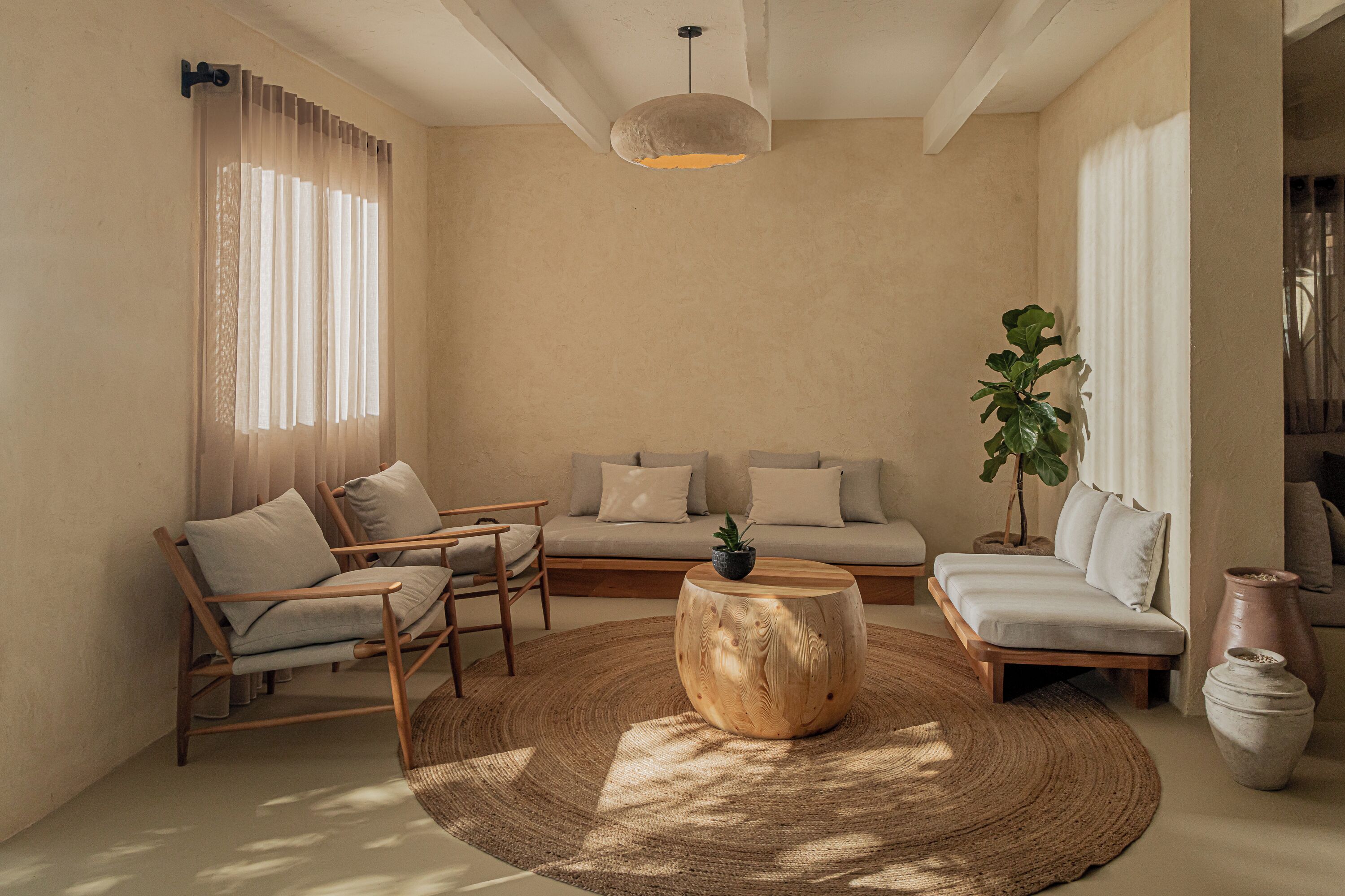 A modern living room with a sofa, chairs, a coffee table, and a large window with curtains.