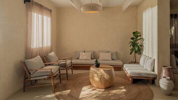 A modern living room with a sofa, chairs, a coffee table, and a large window with curtains.
