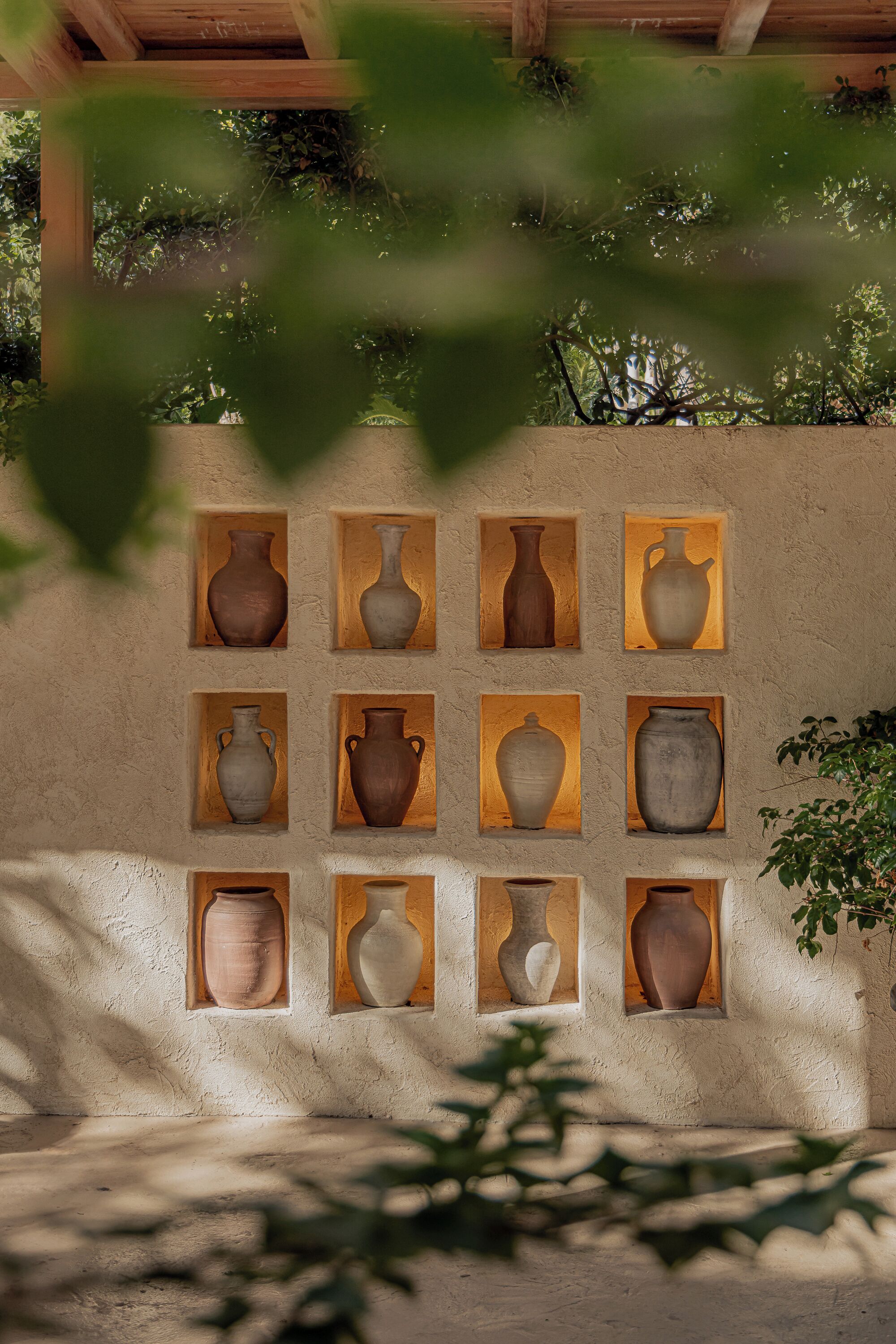 A wall with multiple vases displayed in wooden frames.