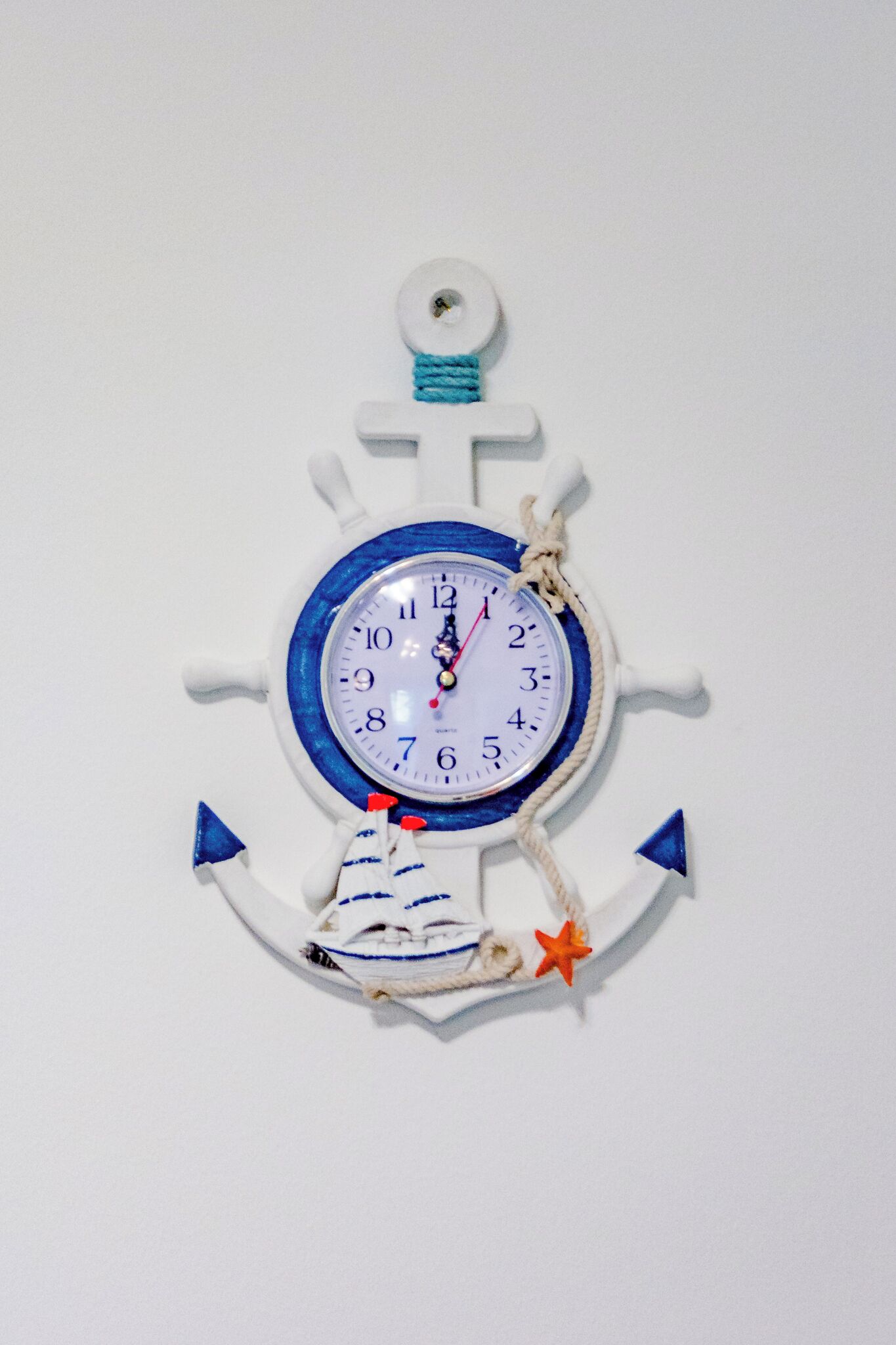 Een wandklok met een nautisch thema, met ankers en een scheepsschroef.