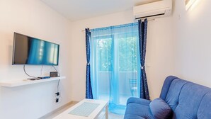 A modern living room with a flat-screen TV, a white coffee table, and a blue sofa. - Apartment Karlo (Kastela)